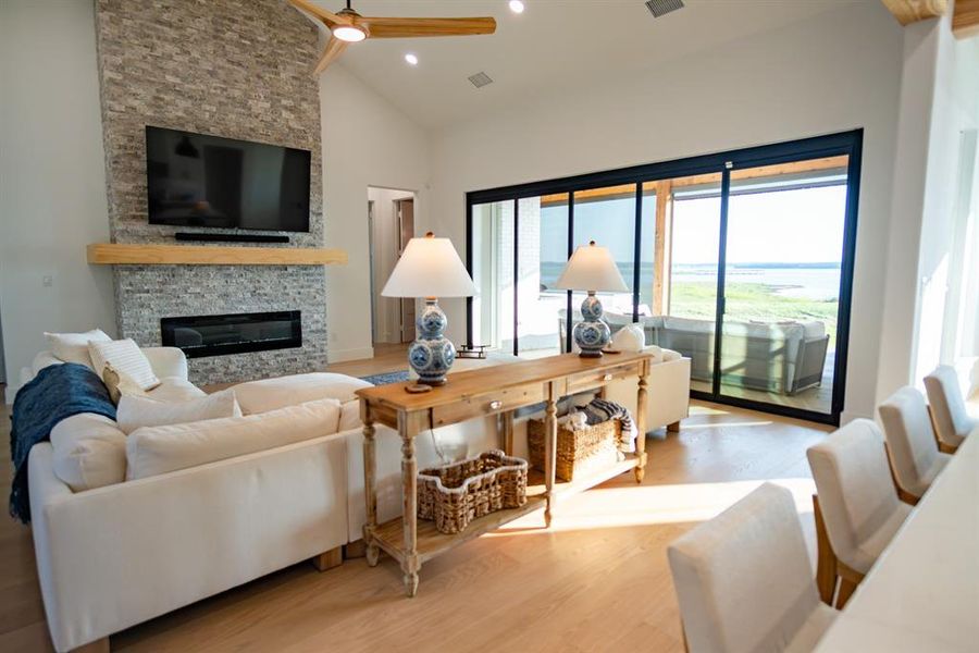 Living area with a fireplace, wood finished floors, high vaulted ceiling, recessed lighting, and a ceiling fan Living area with a fireplace, wood finished floors, high vaulted ceiling, recessed lighting, and a ceiling fan