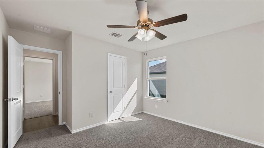 Carpeted interior space featuring light gray walls, a ceiling fan with light fixture, white trim, a single window, and a white paneled door Carpeted interior space featuring light gray walls, a ceiling fan with light fixture, white trim, a single window, and a white paneled door