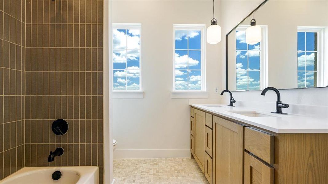 Full bathroom with tile floors, tiled shower / bath, vanity, and toilet