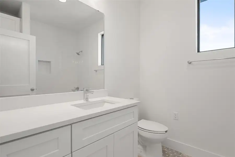 Bathroom featuring plenty of natural light, a tile shower, vanity, and tile patterned flooring