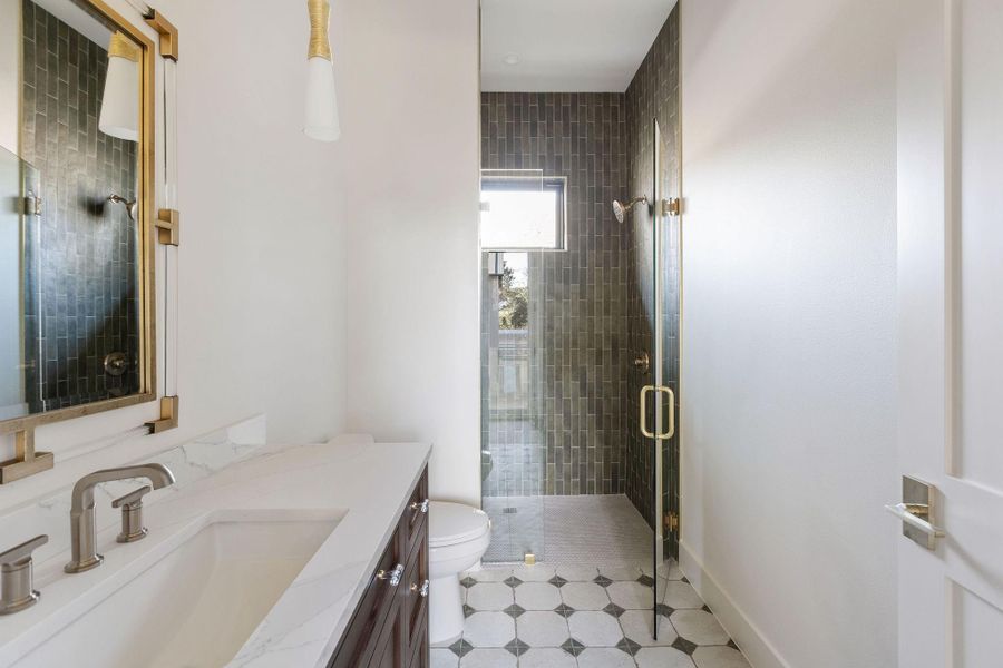 Downstairs guest suite bathroom with Forest Green Porcelain Tile, Quartz Countertops, and Brizo Litze Collection Faucet and Shower in Luxe Gold