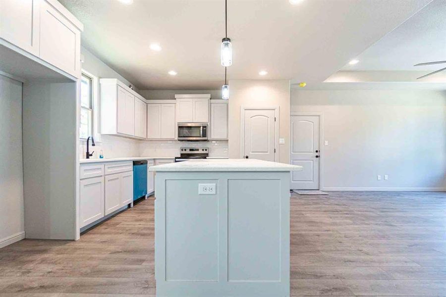 Kitchen with white cabinets, decorative light fixtures, decorative backsplash, recessed lighting, and appliances with stainless steel finishes