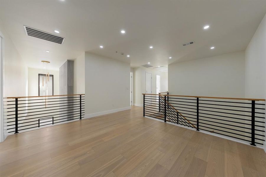 loft with light wood-style floors and recessed lighting