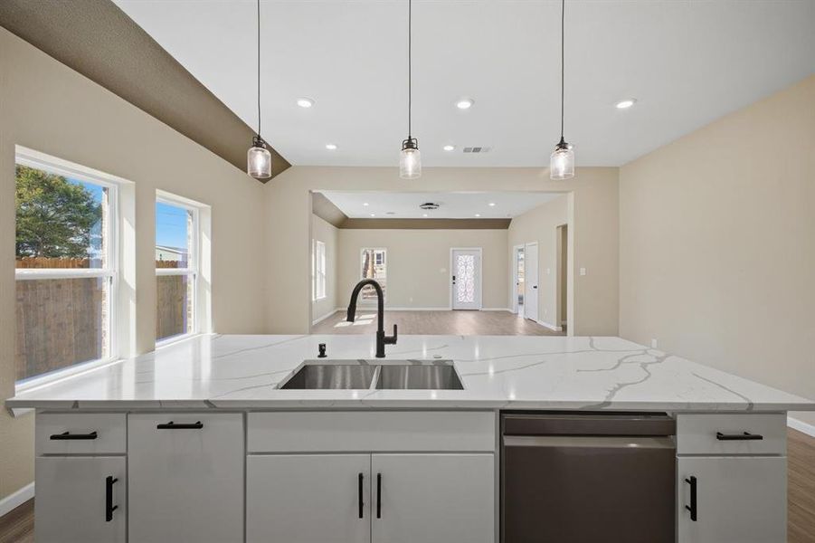 Kitchen featuring white cabinets, dark wood-type flooring, dishwasher, open floor plan, and light stone countertops Kitchen featuring white cabinets, dark wood-type flooring, dishwasher, open floor plan, and light stone countertops