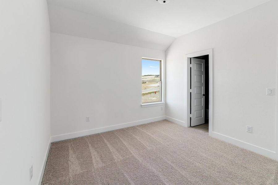 Unfurnished bedroom with baseboards, light carpet, and lofted ceiling Unfurnished bedroom with baseboards, light carpet, and lofted ceiling
