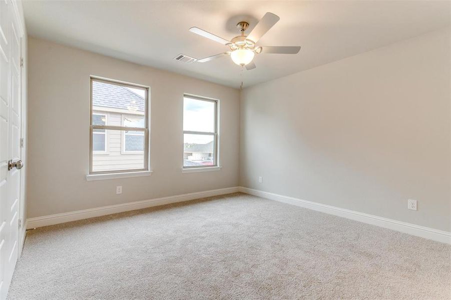 Empty room with light colored carpet and ceiling fan