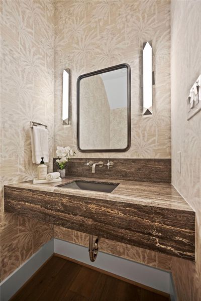 Sophisticated power room featuring a dark stone countertop and modern wall sconces. Sophisticated power room featuring a dark stone countertop and modern wall sconces.