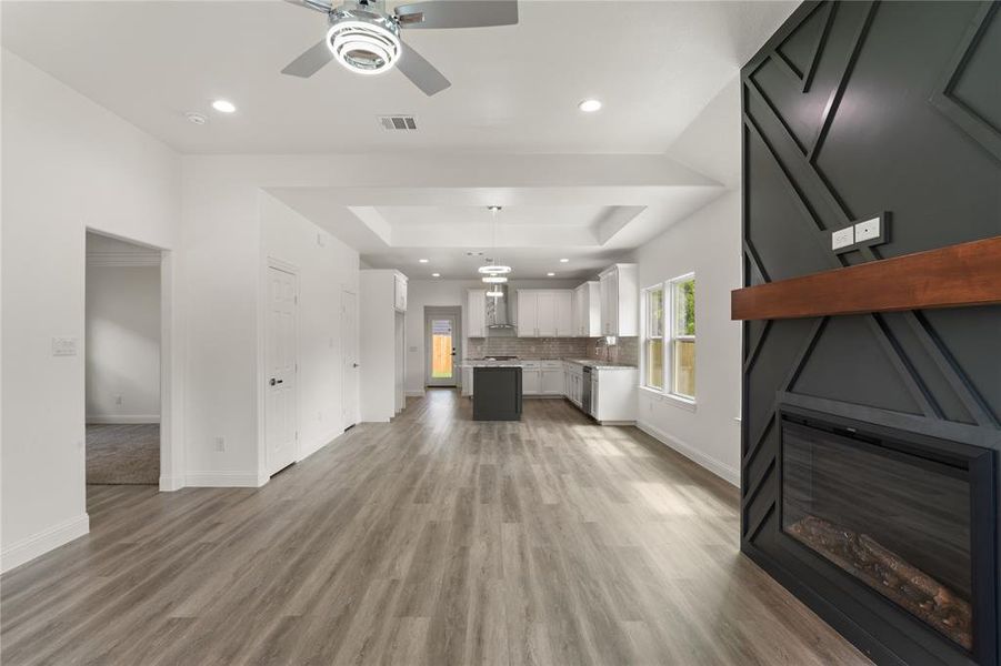 Spacious open-concept living area featuring wood-finish flooring, a contemporary ceiling fan, and recessed lighting