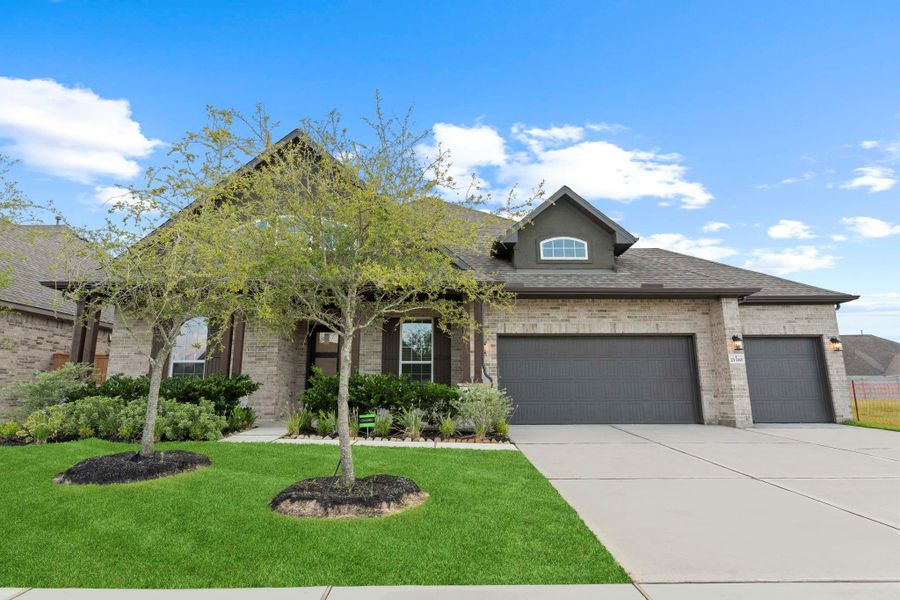 Beautifully landscaped front yard with mature trees and lush greenery, showcasing the home’s charming architecture on a desirable cul-de-sac lot. A picture-perfect first impression.  Sprinkler System to help keep this yard looking as beautiful as it is now!