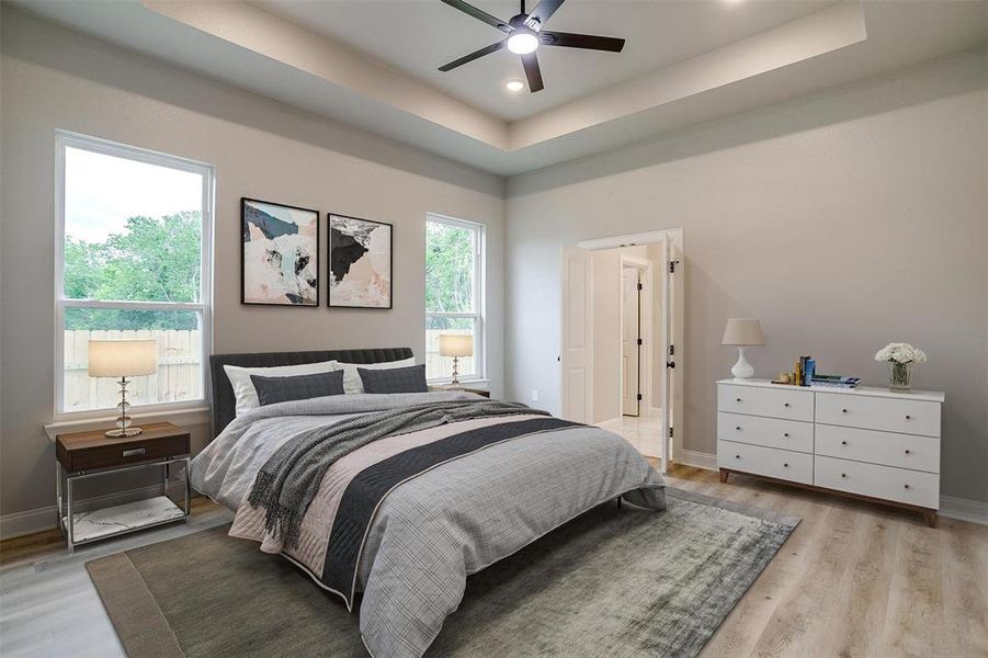 Bedroom with light wood-type flooring, baseboards, and a tray ceiling Bedroom with light wood-type flooring, baseboards, and a tray ceiling