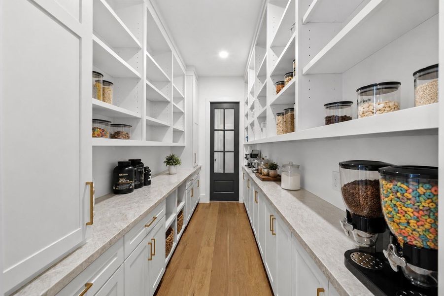 Oversized walk-in pantry with extensive shelving, cabinetry, and countertop workspace.
