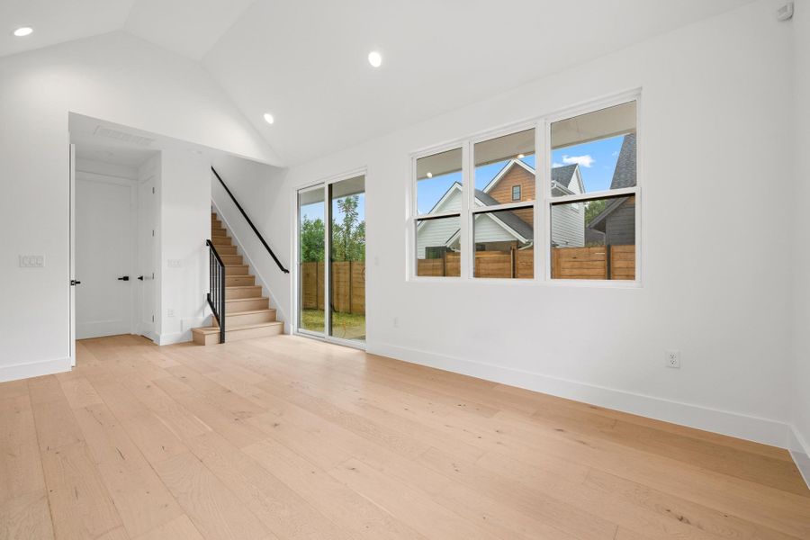 Empty room featuring stairway, recessed lighting, light wood finished floors, and high vaulted ceiling Empty room featuring stairway, recessed lighting, light wood finished floors, and high vaulted ceiling