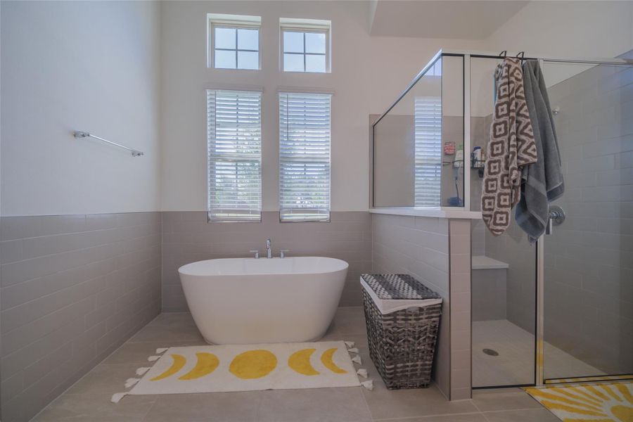 Indulge in relaxation with this primary bathroom's deep soaking tub and separate glass-enclosed shower.