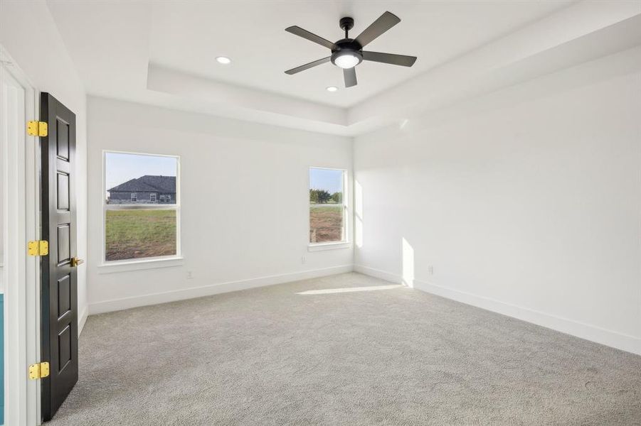 Empty room with light colored carpet, a raised ceiling, recessed lighting, and a ceiling fan Empty room with light colored carpet, a raised ceiling, recessed lighting, and a ceiling fan