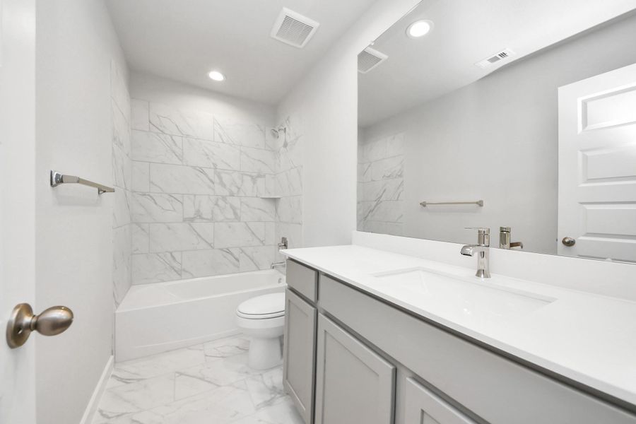 Secondary bath features tile flooring, bath/shower combo with tile surround, light stained wood cabinets, beautiful light countertop. Secondary bath features tile flooring, bath/shower combo with tile surround, light stained wood cabinets, beautiful light countertop.