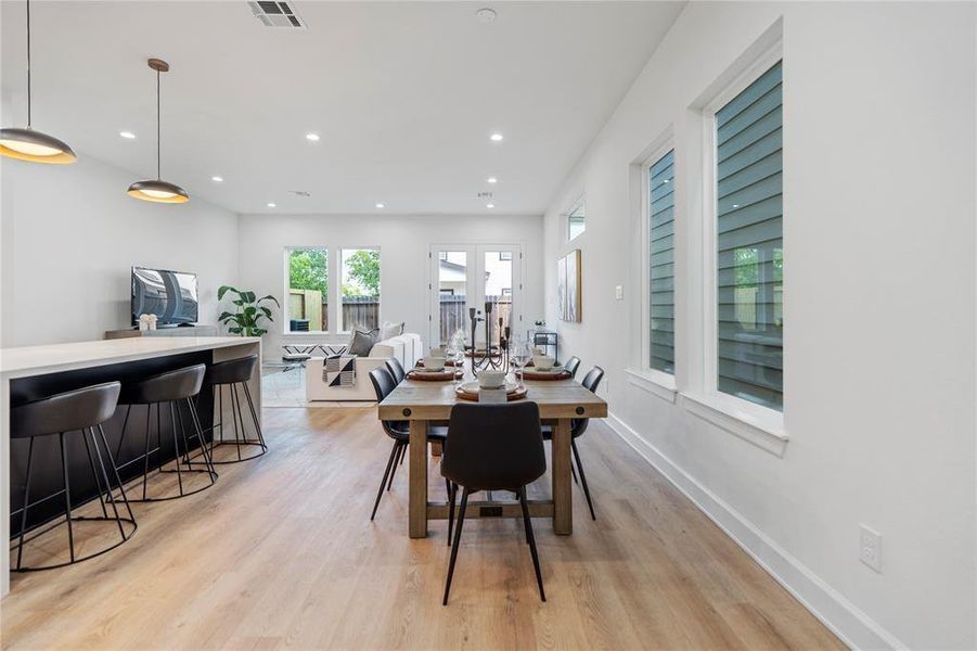 Open-concept dining and living area with sleek hardwood floors, modern pendant lighting, and expansive windows for abundant natural light. Open-concept dining and living area with sleek hardwood floors, modern pendant lighting, and expansive windows for abundant natural light.