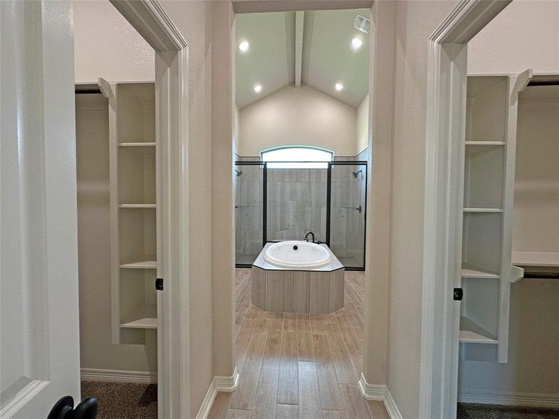 Bathroom with a walk in closet, a shower stall, built in shelves, and a bath