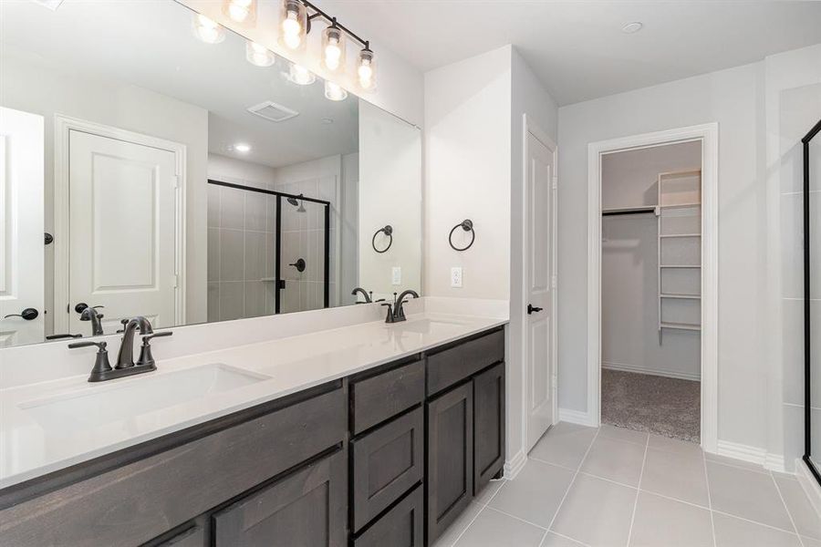 Bathroom featuring tile patterned floors, walk in shower, and dual bowl vanity