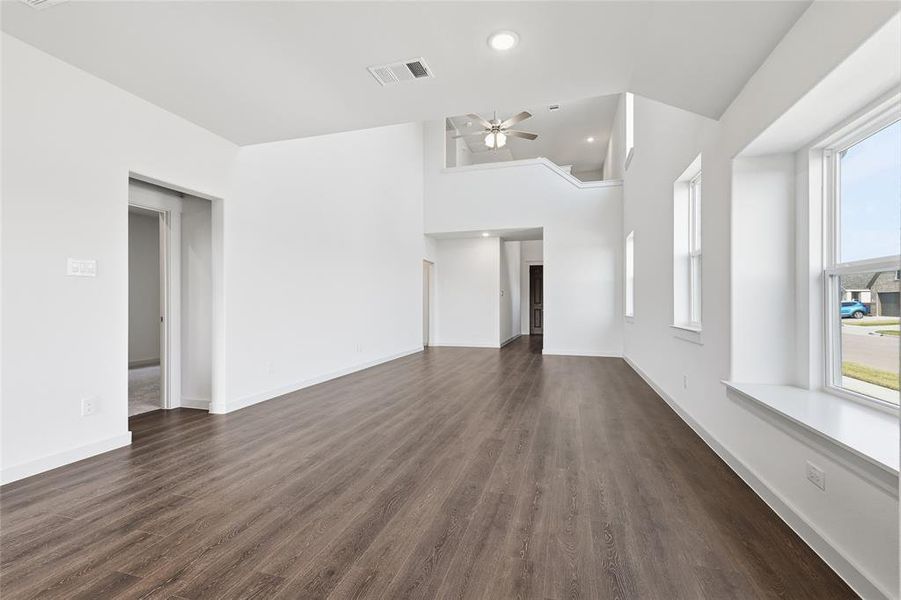 Unfurnished living room featuring dark wood-style flooring, high vaulted ceiling, a ceiling fan, and recessed lighting Unfurnished living room featuring dark wood-style flooring, high vaulted ceiling, a ceiling fan, and recessed lighting