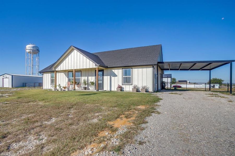 Modern inspired farmhouse featuring siding, driveway, a shingled roof, covered porch, and a carport Modern inspired farmhouse featuring siding, driveway, a shingled roof, covered porch, and a carport