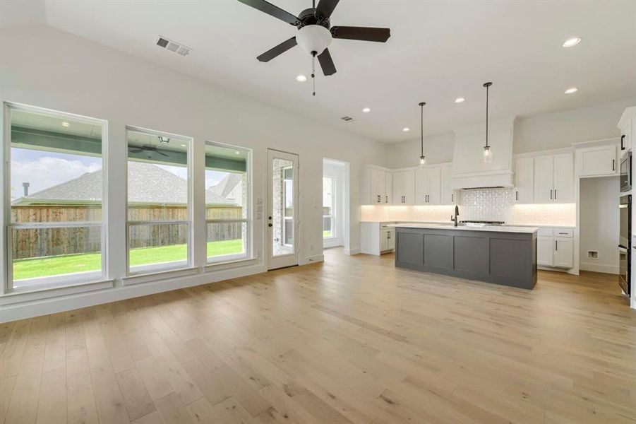 Open-concept interior featuring light wood-finish flooring, a contemporary kitchen, and a wall of windows Open-concept interior featuring light wood-finish flooring, a contemporary kitchen, and a wall of windows
