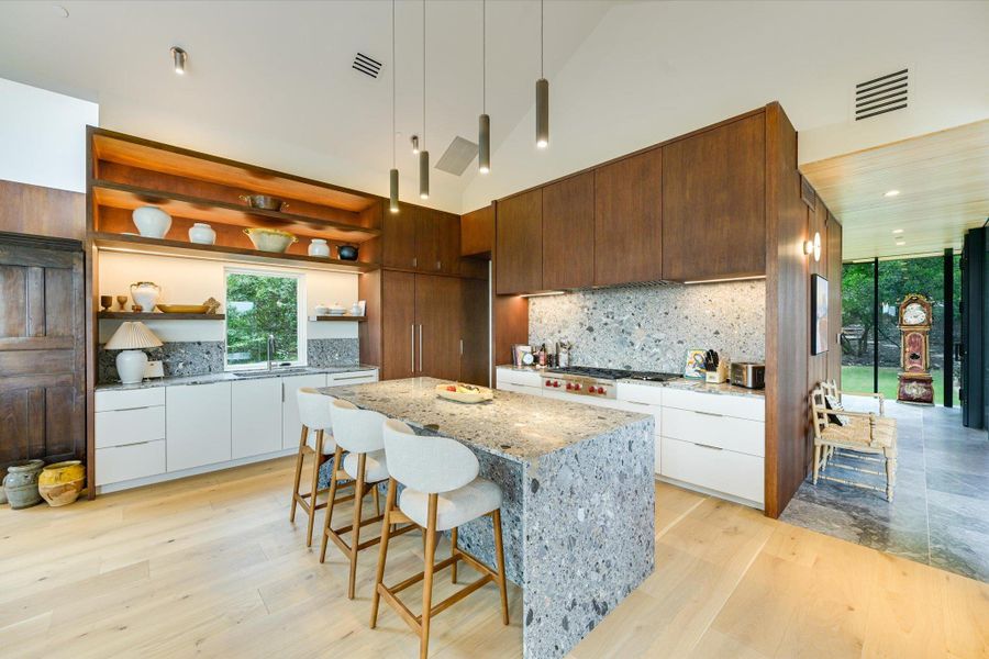 Kitchen featuring modern cabinets, light stone counters, open shelves, white cabinets, and high vaulted ceiling