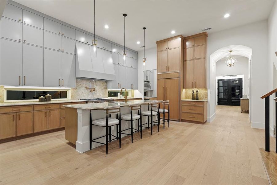 Kitchen with a kitchen breakfast bar, backsplash, arched walkways, an island with sink, and recessed lighting