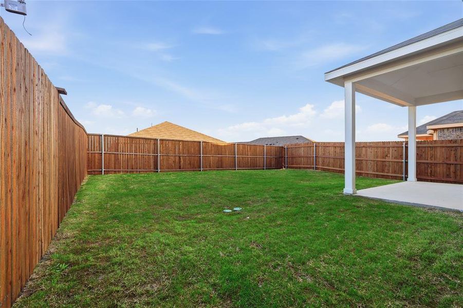 Spacious backyard featuring a covered patio, a full privacy fence, and a generous lawn area Spacious backyard featuring a covered patio, a full privacy fence, and a generous lawn area
