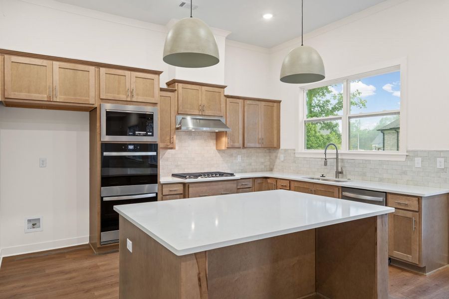 Kitchen featuring light wood-finish cabinetry, white quartz countertops, stainless steel appliances, and a tiled backsplash Kitchen featuring light wood-finish cabinetry, white quartz countertops, stainless steel appliances, and a tiled backsplash