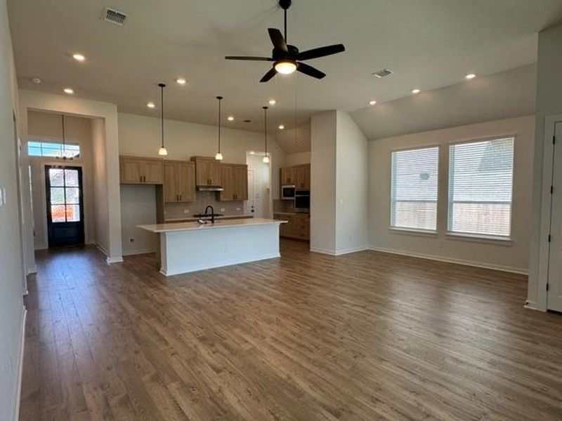 A grand, open-concept living space integrates a modern kitchen and dining area under soaring ceilings.