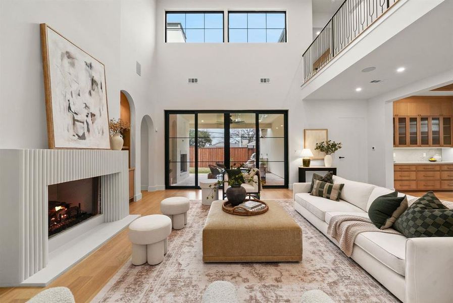 Living room with a lit fireplace, wood finished floors, and arched walkways Living room with a lit fireplace, wood finished floors, and arched walkways