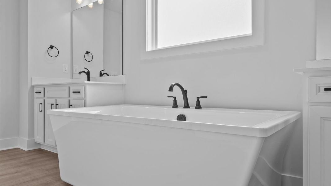 Highly functional and elegant en-suite with separate vanities, tiled walk-in shower, and soaking tub