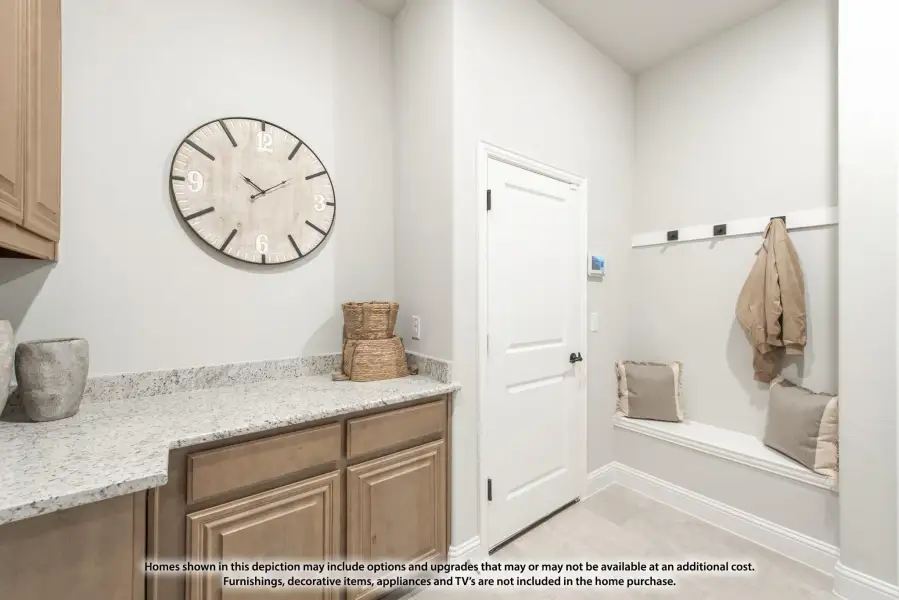 Mudroom with built-in bench, wall hooks, and wood cabinets with granite countertop