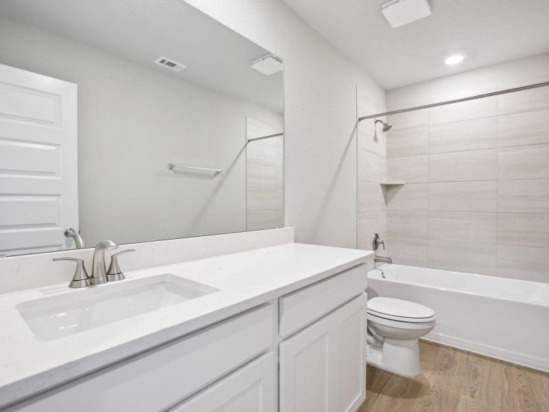 Bathroom with wood finished floors, vanity, toilet, shower / bath combination, and recessed lighting Bathroom with wood finished floors, vanity, toilet, shower / bath combination, and recessed lighting