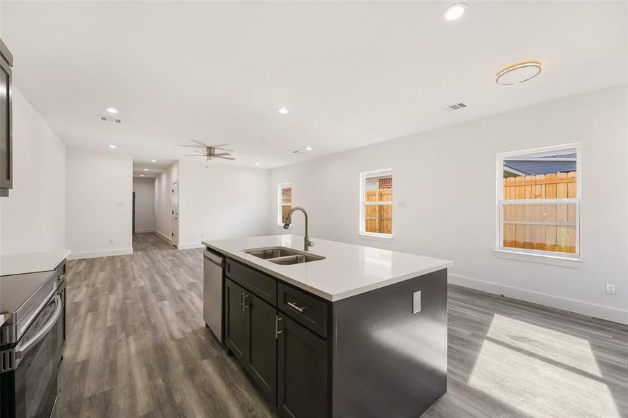 Kitchen with open floor plan, recessed lighting, a ceiling fan, light wood-style floors, and a center island with sink