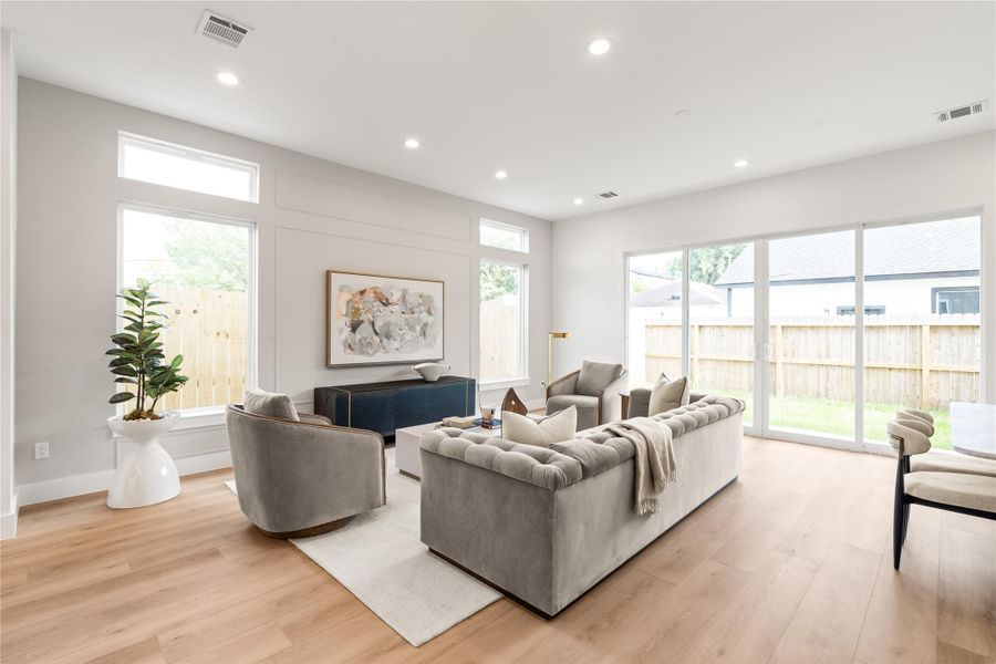 Oversized windows and two full sliding doors bring in natural light from two directions and open the room directly to the backyard. The space is generous enough for real furniture layouts without feeling like it's fighting for room.
