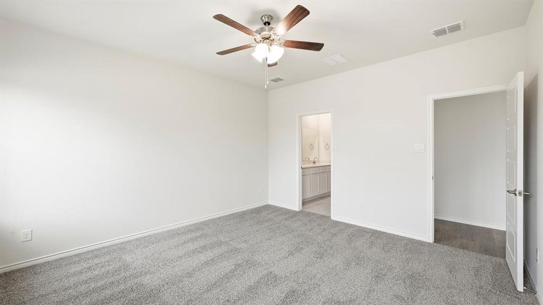 Unfurnished bedroom featuring carpet floors, ceiling fan, and ensuite bath