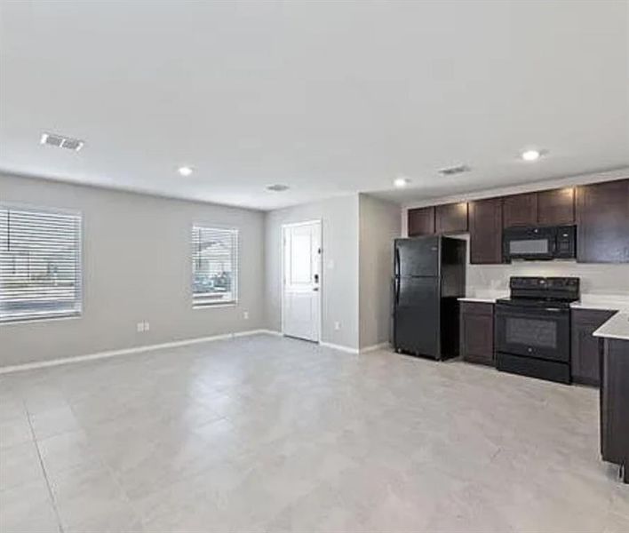 Kitchen with black appliances, light countertops, dark brown cabinets, open floor plan, and recessed lighting