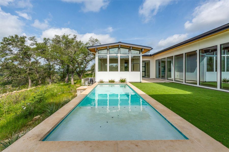 A tranquil inground pool with adjacent grassy yard creates an inviting outdoor retreat.