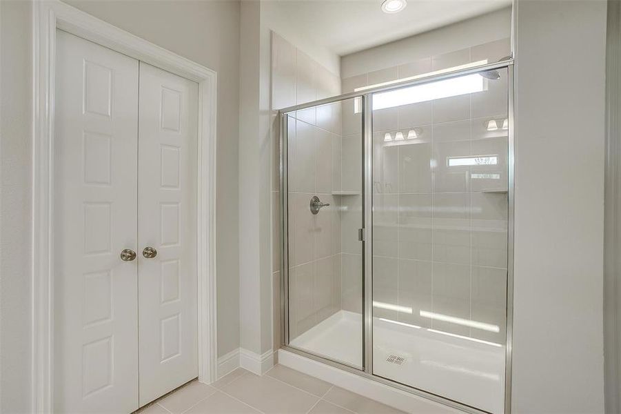 Bathroom featuring tile patterned flooring and a stall shower Bathroom featuring tile patterned flooring and a stall shower