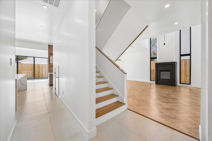 Modern interior featuring an elegant staircase, open living area with a sleek fireplace, and large windows for natural light. Modern interior featuring an elegant staircase, open living area with a sleek fireplace, and large windows for natural light.