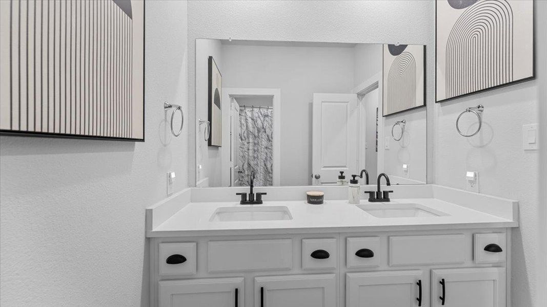 Bathroom featuring a textured wall, double vanity, and a shower with shower curtain Bathroom featuring a textured wall, double vanity, and a shower with shower curtain