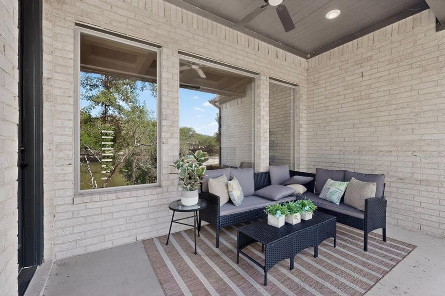 Covered patio with light-colored brick exterior, concrete flooring, and an overhead ceiling fan