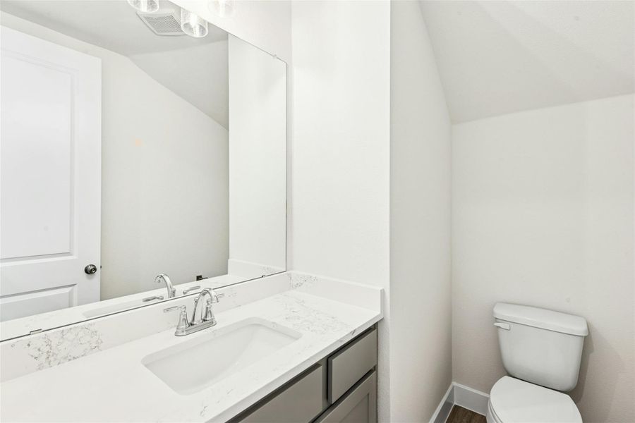 Half bathroom with vanity and vaulted ceiling