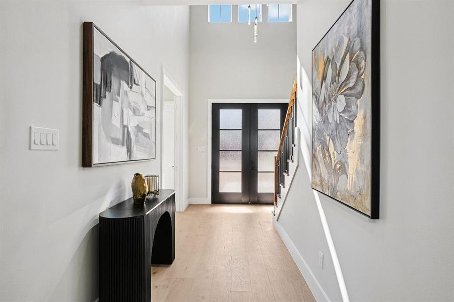 Foyer featuring french doors, light wood-style flooring, and a high ceiling