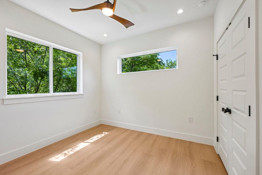 A well-lit bedroom features wood based laminate flooring and abundant natural light from multiple windows. A well-lit bedroom features wood based laminate flooring and abundant natural light from multiple windows.