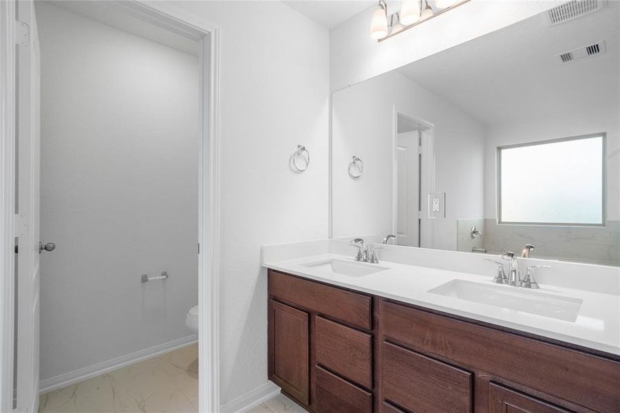 This primary bathroom is definitely move-in ready! Featuring stained cabinets with light countertops with dual vanities, high ceilings, custom paint, tile flooring, sleek and dark modern finishes.