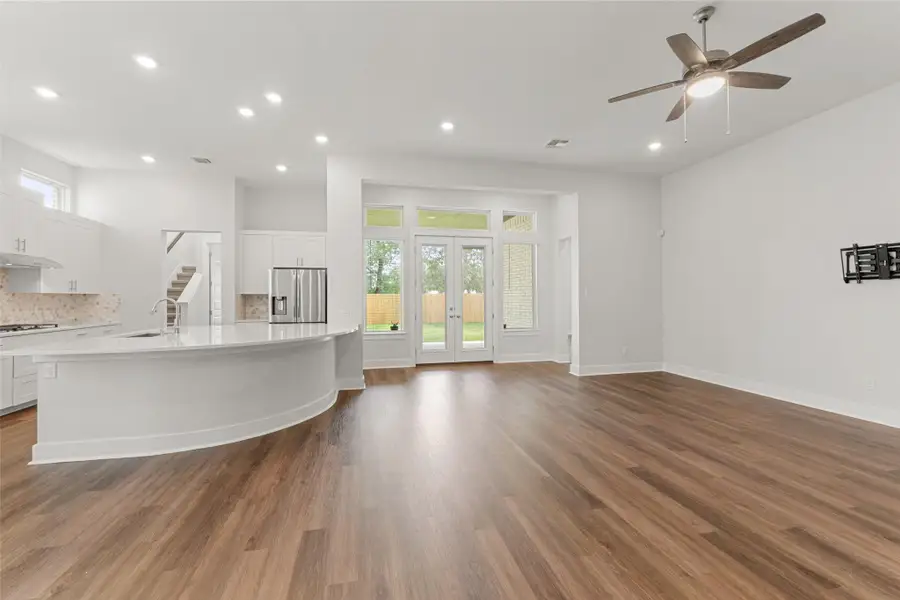 Unfurnished living room with recessed lighting, ceiling fan, a sink, wood finished floors, and french doors Unfurnished living room with recessed lighting, ceiling fan, a sink, wood finished floors, and french doors