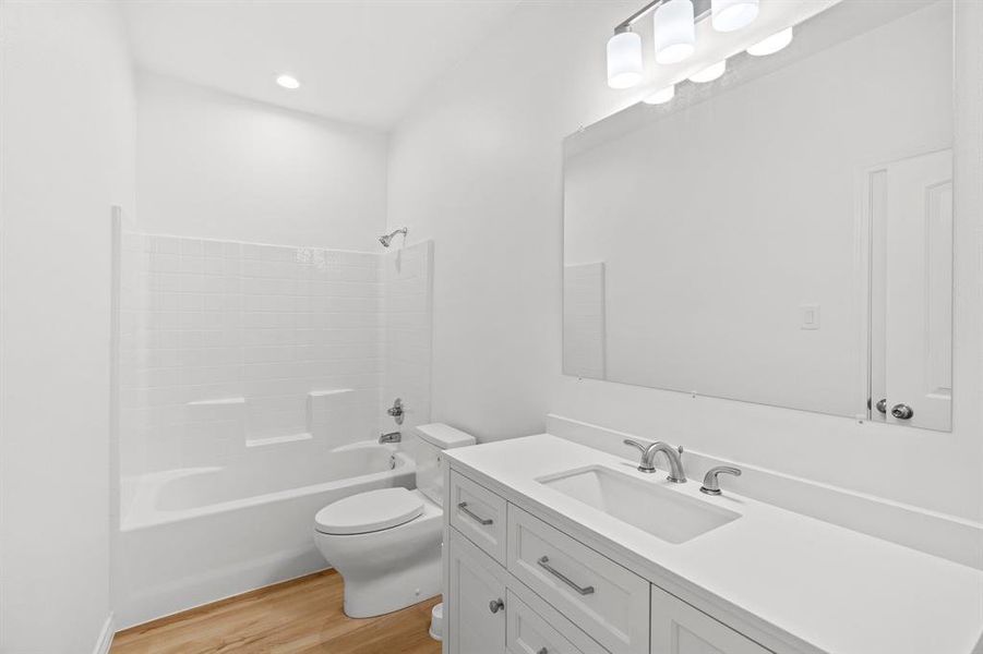 Full bathroom with vanity, wood finished floors, and bathing tub / shower combination Full bathroom with vanity, wood finished floors, and bathing tub / shower combination