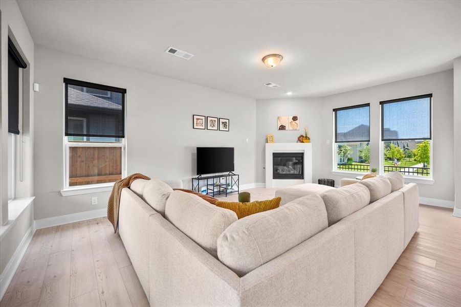 Living area featuring light wood finished floors and a glass covered fireplace Living area featuring light wood finished floors and a glass covered fireplace